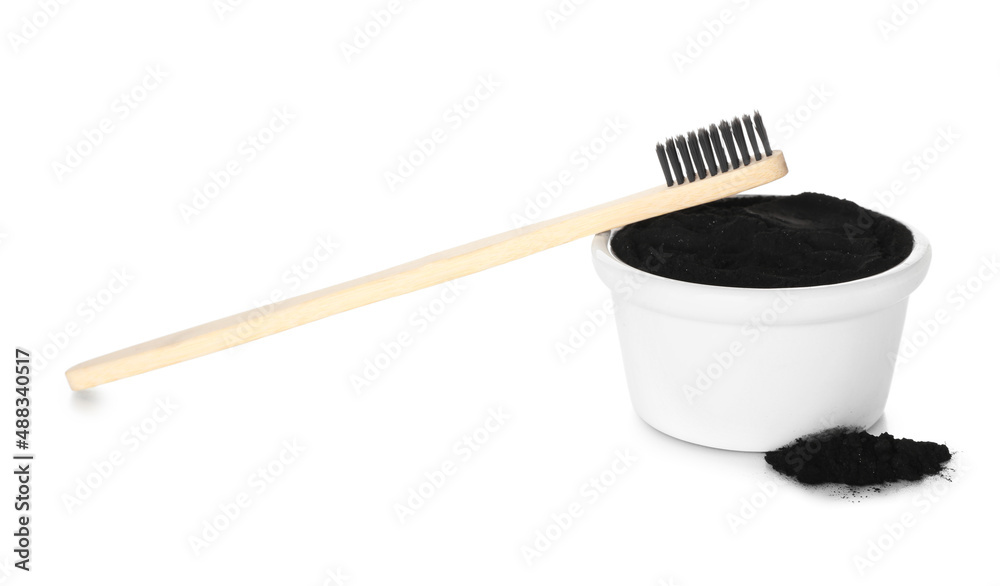 Bowl with activated charcoal tooth powder and toothbrush on white background