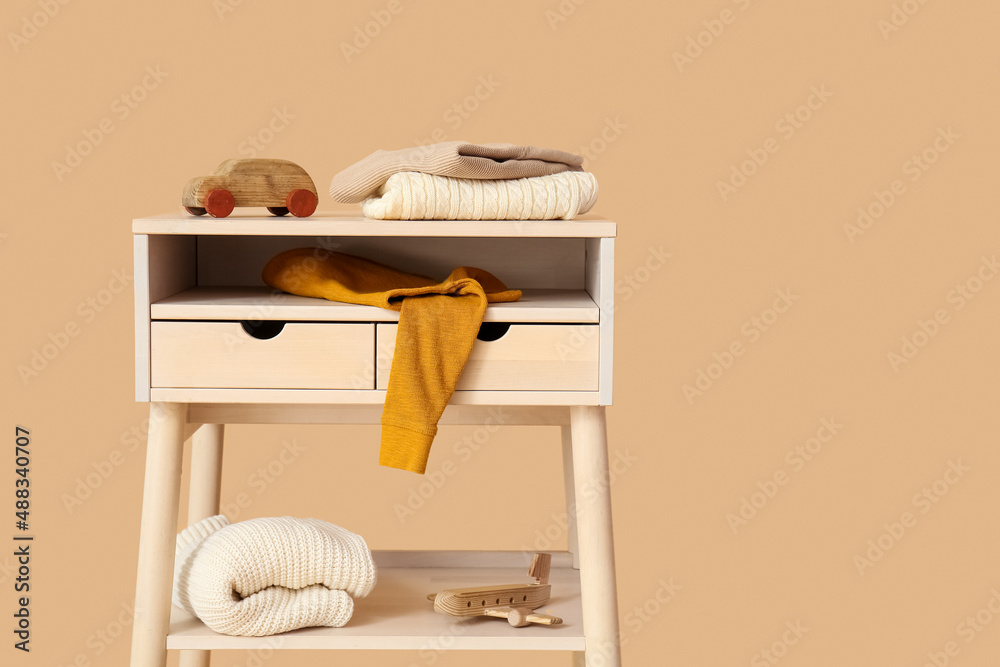 Standing desk with childrens sweaters and toys on color background