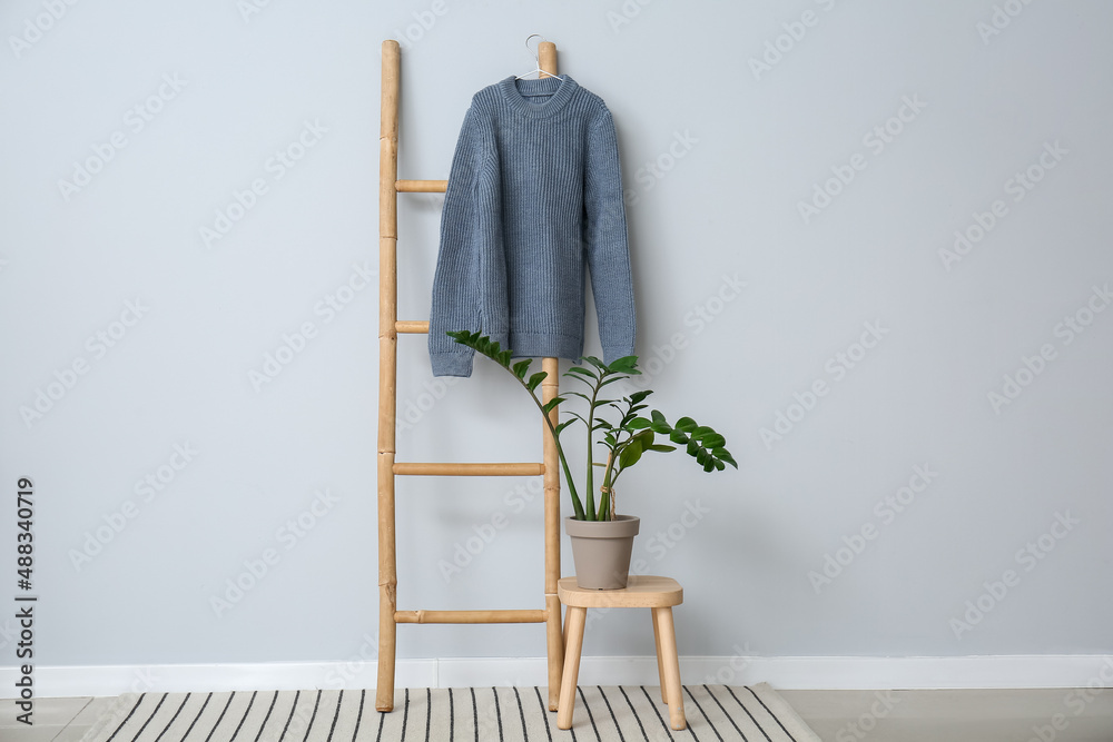 Sweater hanging on ladder near color wall in room