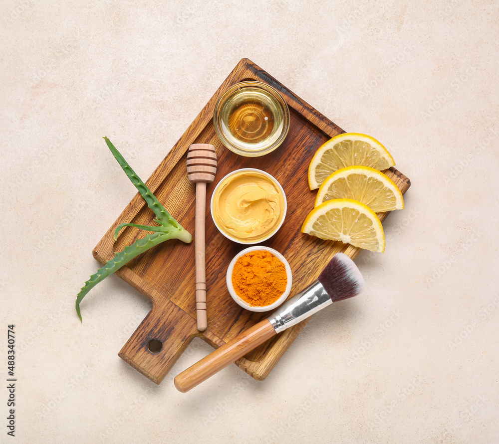 Board with turmeric mask, powder, honey, lemon and makeup brush on light background