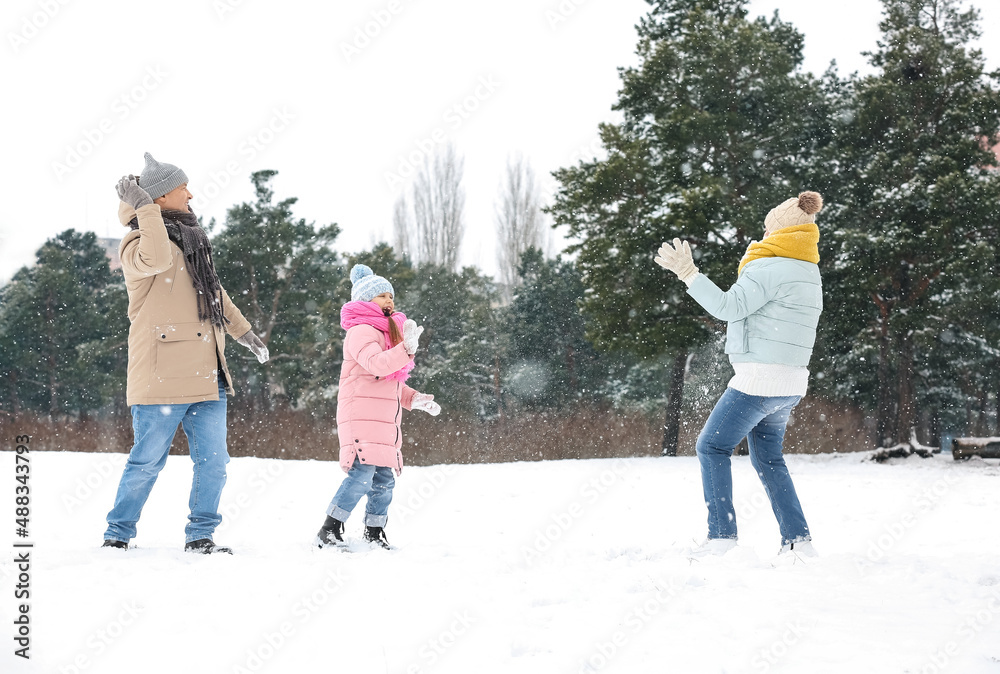 Little girl and her grandparents throwing snowballs on snowy winter day