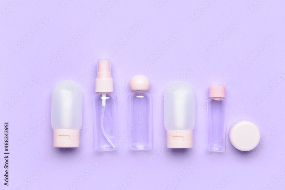 Set of empty travel bottles on lilac background