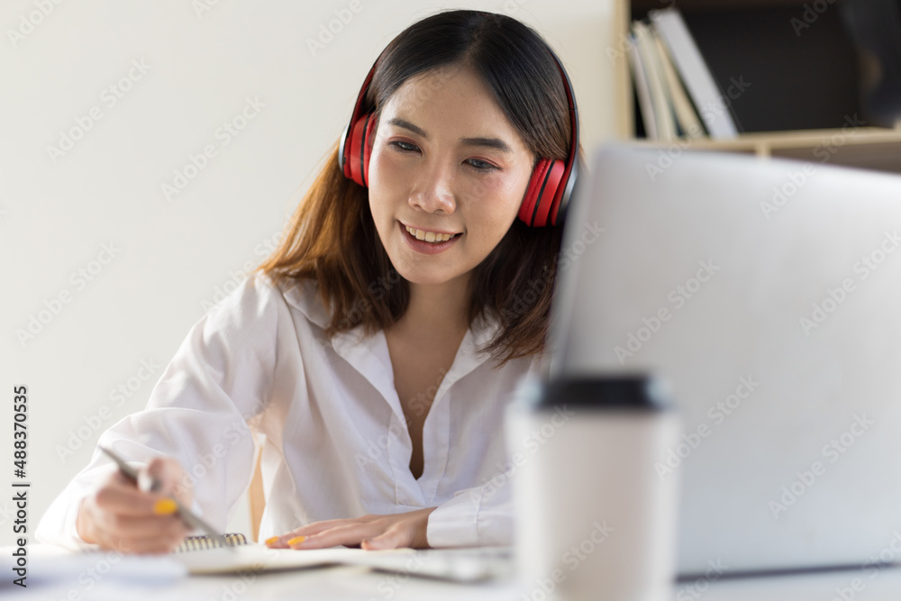 Work from home concept. Woman is working on a laptop, meeting online and writing learning notes in a