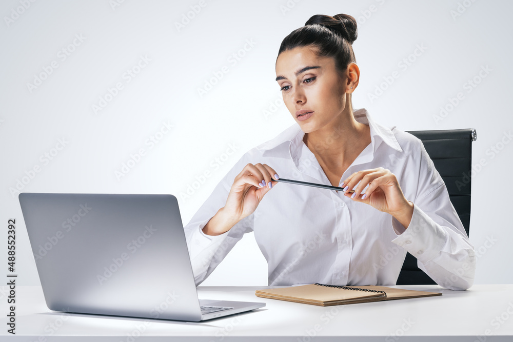 Online education and studying concept with pretty young woman sitting at white table, looking at lap