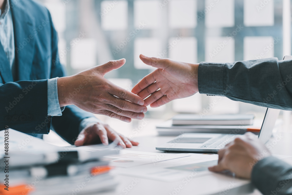 Business people shaking hands finishing up meeting or negotiation in sunny office. Business handshak