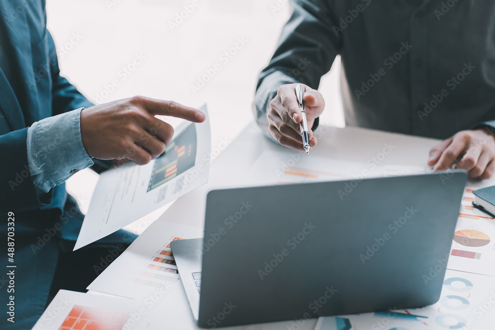 Business team two colleagues discussing new plan financial graph data on office table with laptop an