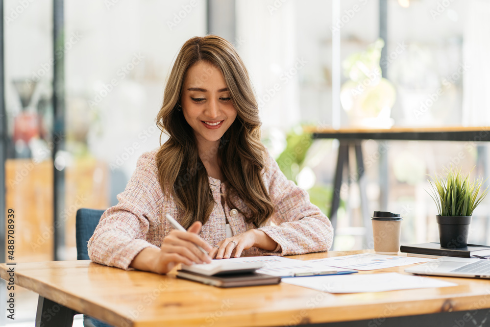 Business women using calculator at working with financial report.