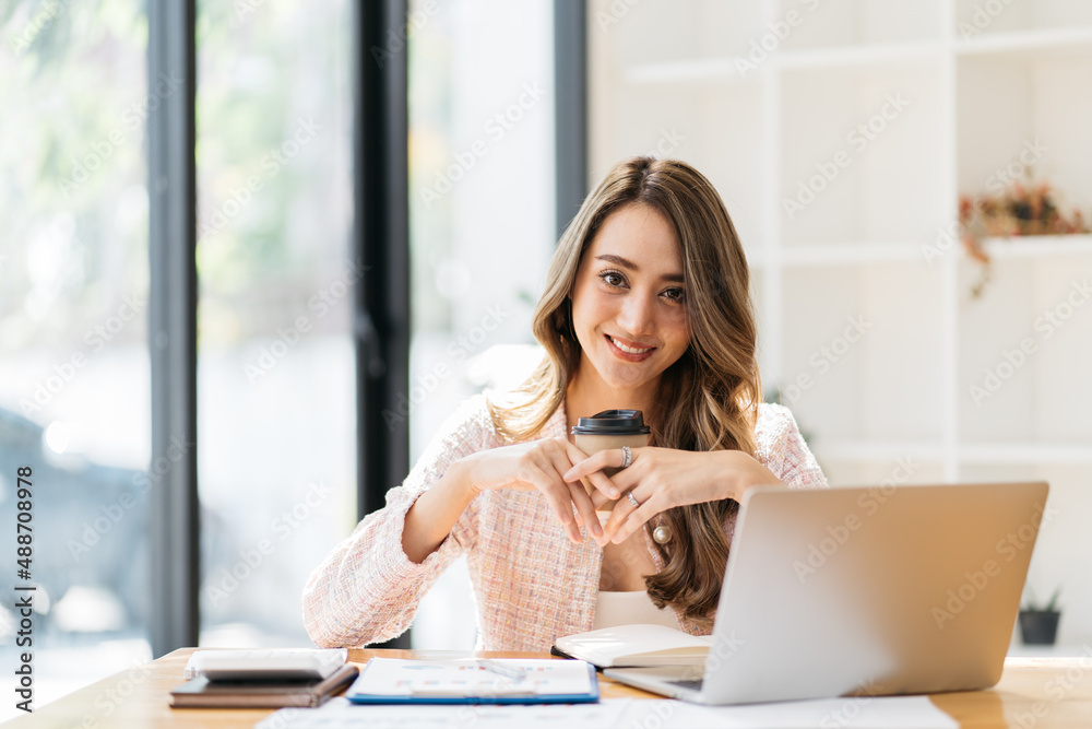 Portrait young attractive beautiful asia female sit on desk smile to camera work at home remotely co