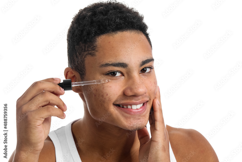 Young African-American guy with serum for skin care on white background