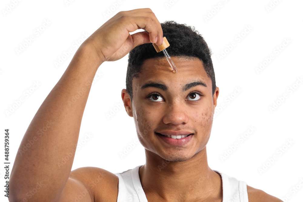 Young African-American guy with serum for skin care on white background