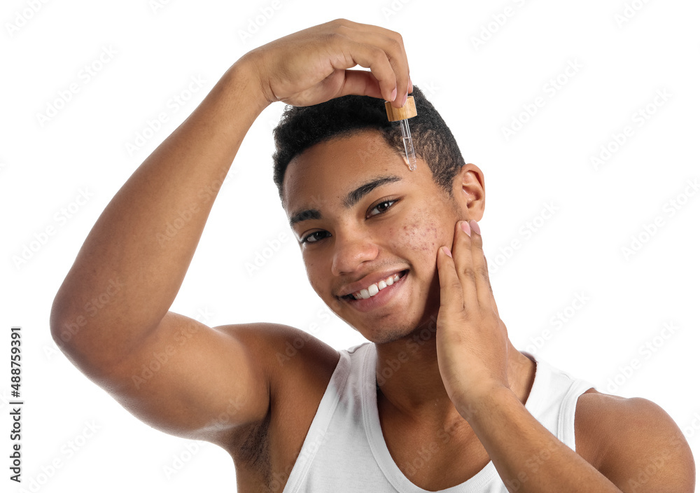 Young African-American guy with serum for skin care on white background