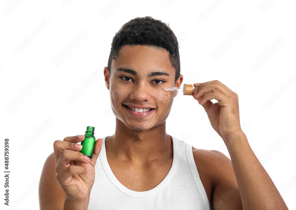 Young African-American guy with serum for skin care on white background