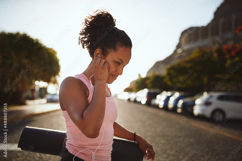 Sporty woman listening to music and carrying a yoga mat