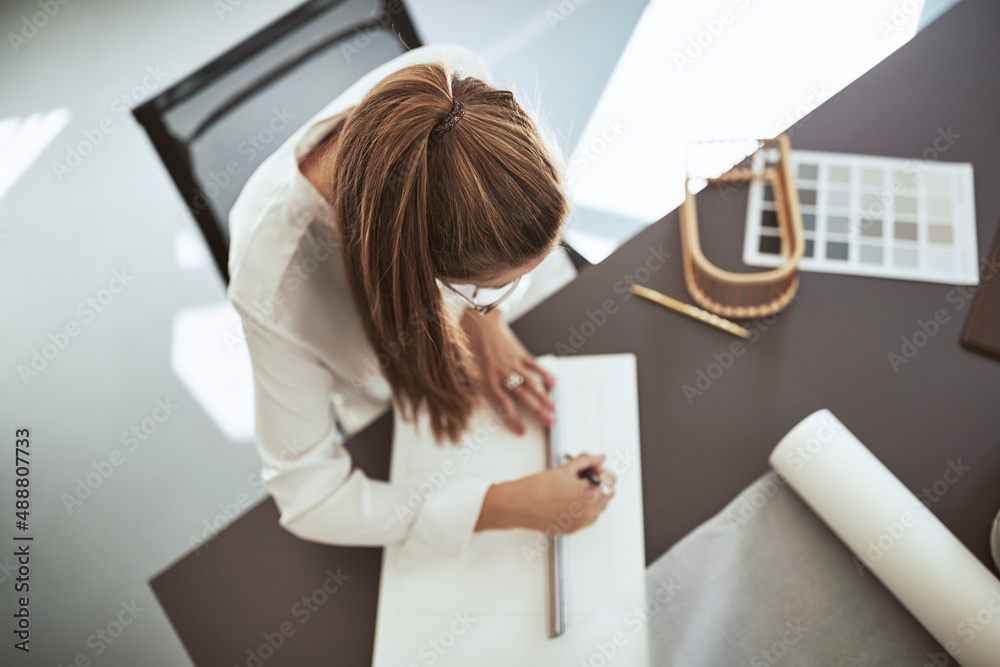 年轻的女建筑师在办公桌上起草图纸