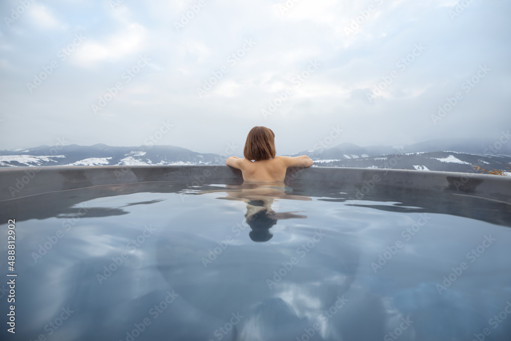 年轻女子冬天在山上的热水浴缸里洗澡。在热水浴缸里休息和恢复的概念