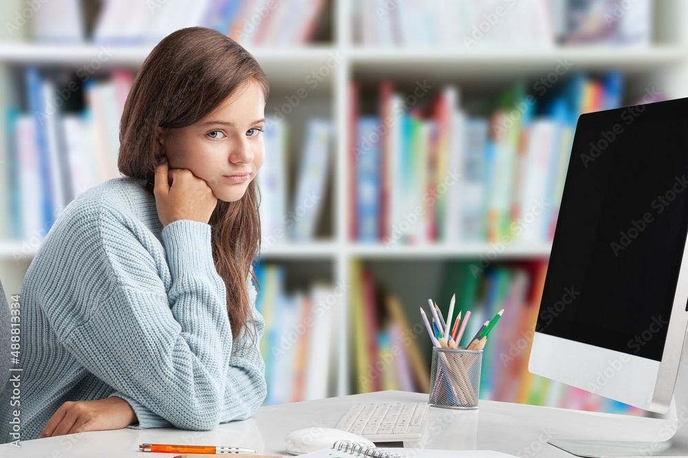 Exhautsed kid teen doing homework alone, sitting at table full of exercise books,