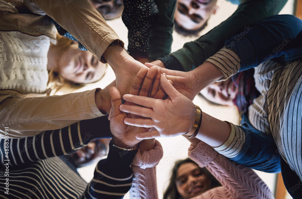 Theres power in unity. Low angle portrait of a group of young friends standing with their hands in a