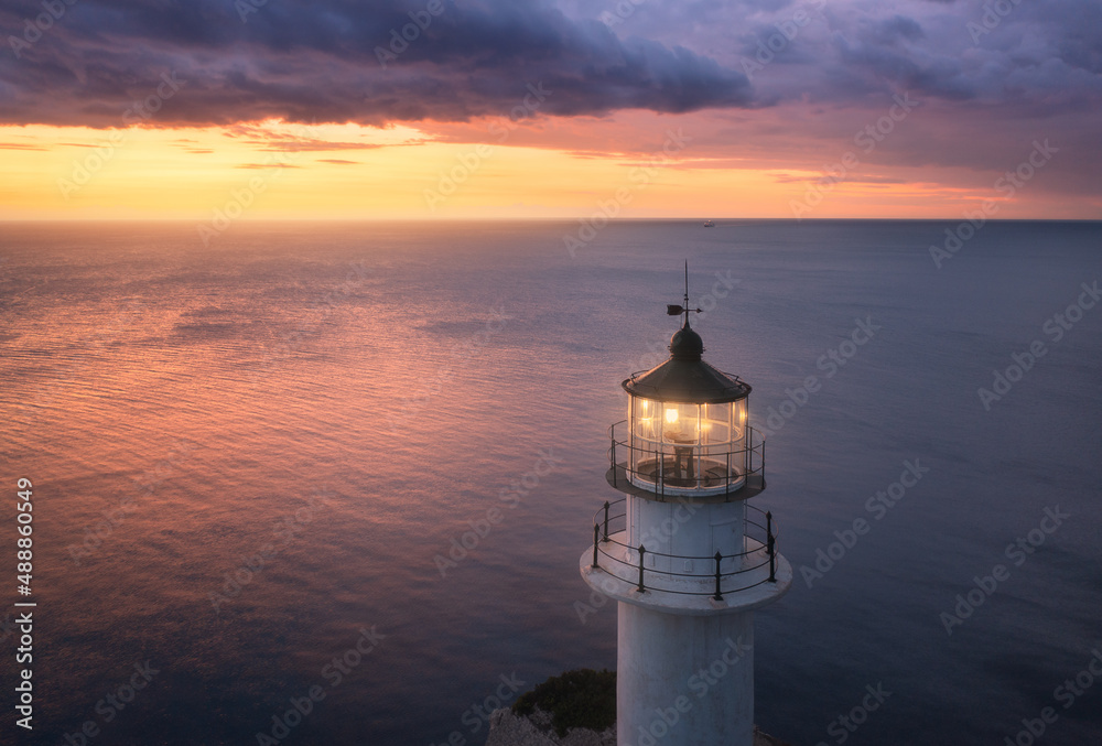 Lighthouse on the mountain peak at colorful sunset in summer. Aerial view. Beautiful lighthouse, lig