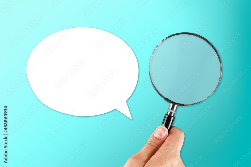 A blank speech bubble and hand holding a magnifying glass on a background.