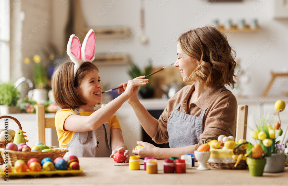 Joyful happy family mom and daughter having fun and fooling around while decorating Easter eggs