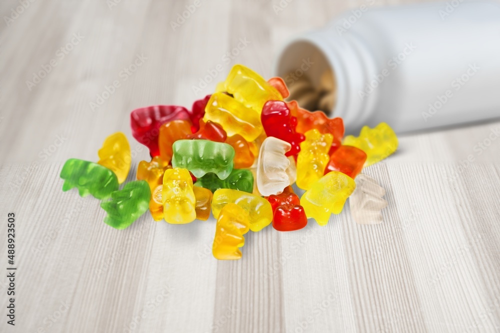 Group of colored multivitamin gummies with the bottle on the desk