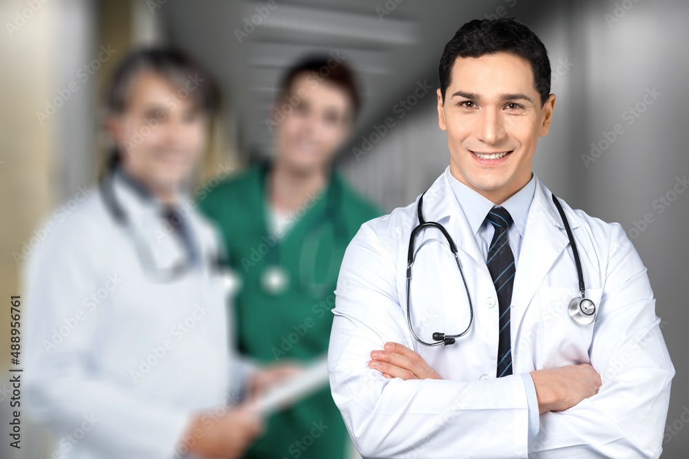 Portrait of happy young nurse in uniform with healthcare team in background. Successful doctor and n