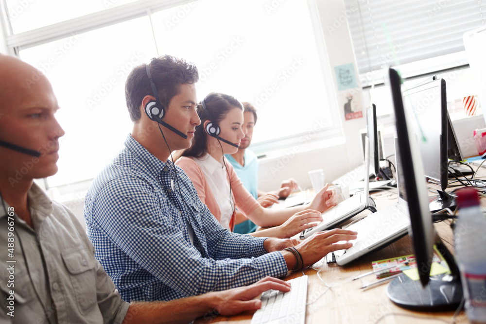 Servicing their clients. Sales assistants at the office working in front of their computers wearing 