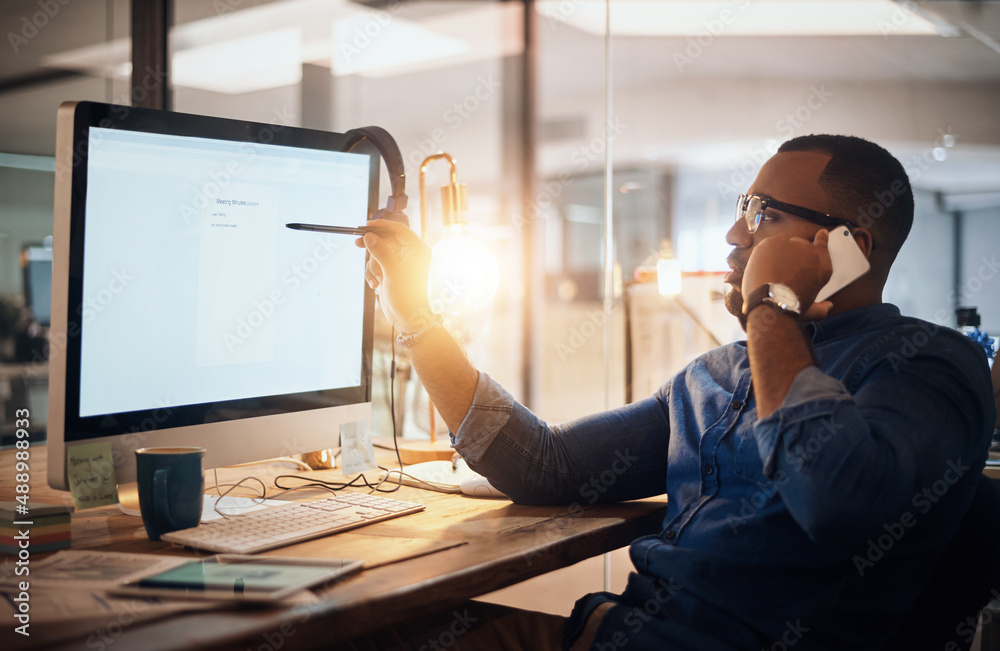 Im working on it as we speak. Shot of a young businessman talking on a cellphone while working on a 