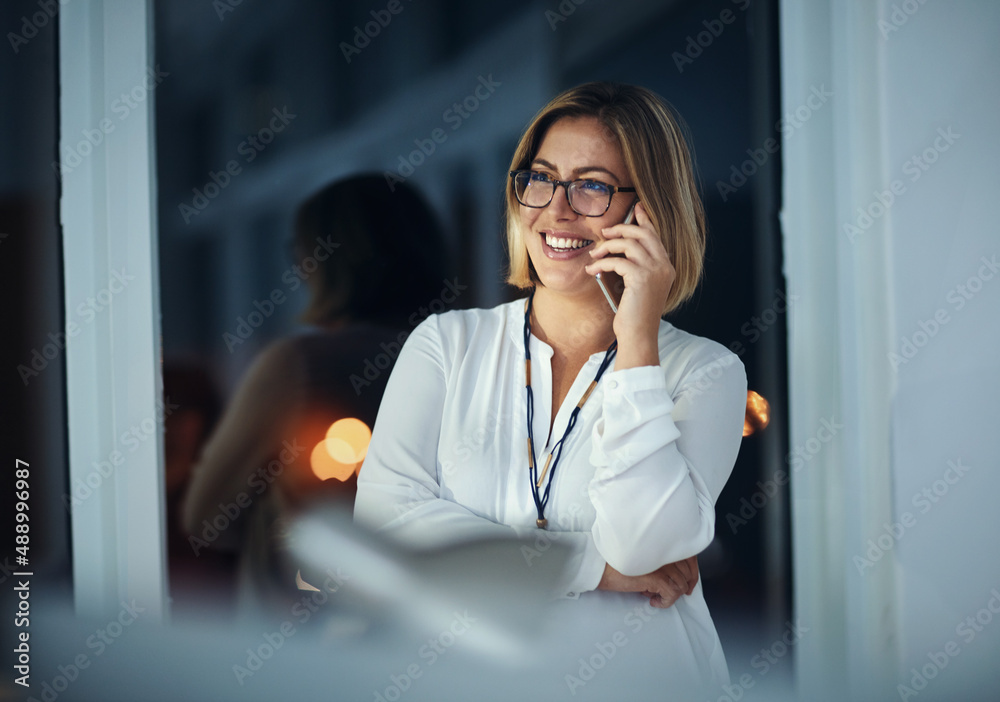 Im coming home. Shot of a businesswoman talking on a mobile phone during a late night at work.