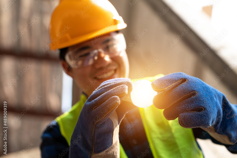 Asian happy electrician with light bulbs and fixing the light Inside remodeled apartment in Construc