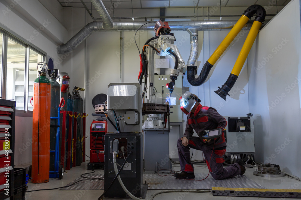 An engineer or worker wear a safety mask control the smart robot welding hand system automated manuf