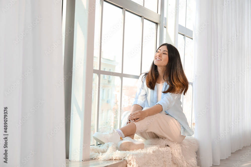 坐在窗台上的漂亮年轻亚洲女人