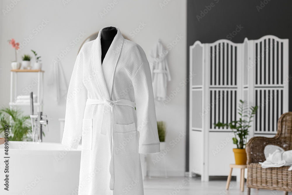 Bathrobe on mannequin in interior of stylish bathroom