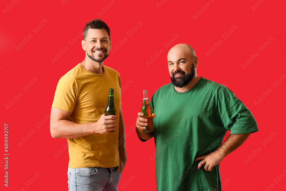 Men drinking beer on red background