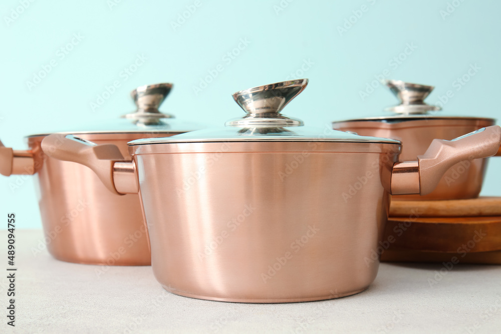 Shiny cooking pots with cutting boards on table against blue background