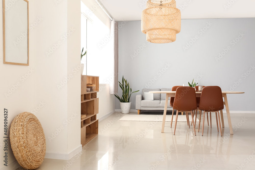 Interior of modern dining room with table, sofa and hanging lamp