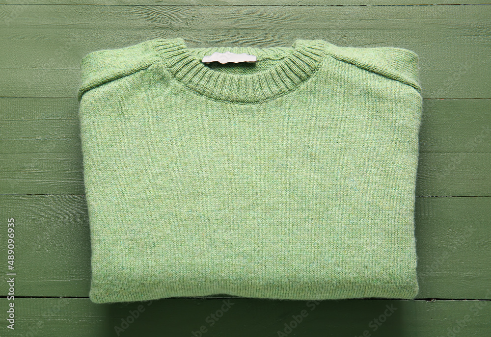 Folded sweater on color wooden background