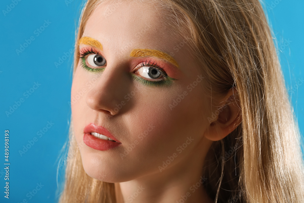 Beautiful girl with unusual eyebrows on color background, closeup