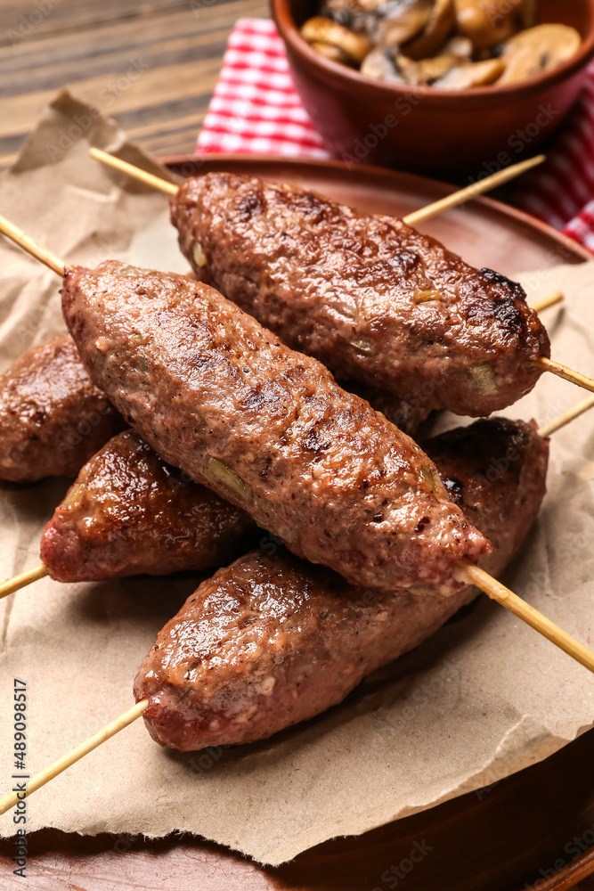 Plate of skewers with tasty lula kebab on table, closeup