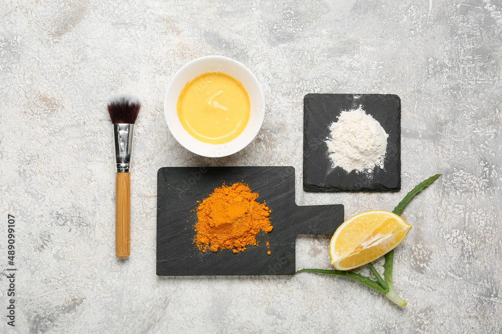 Composition with turmeric mask, powder, lemon and makeup brush on light background