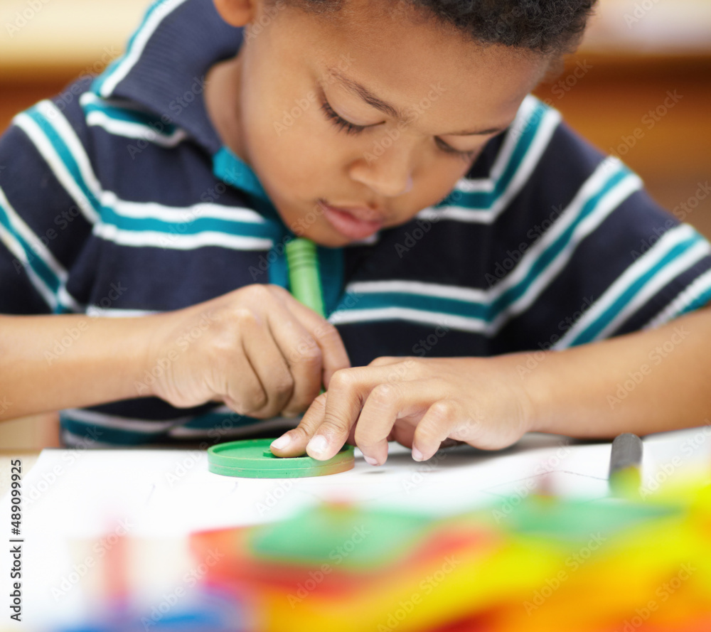 Its creative time. Pre-school african american boy concentrating on his drawings with his crayons an