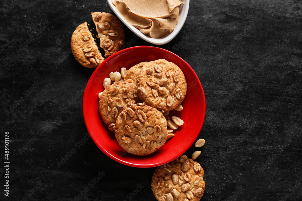 Bowl with tasty peanut cookies on black background