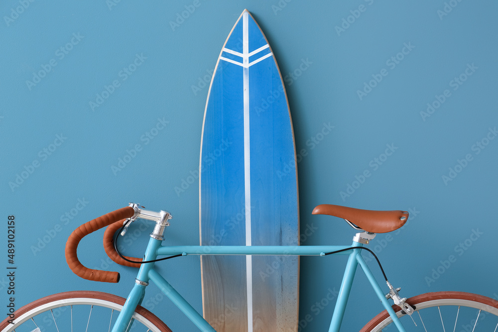 Bicycle and surfboard near color wall