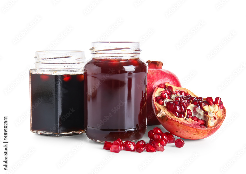 Jars of pomegranate molasses and fresh fruits on white background