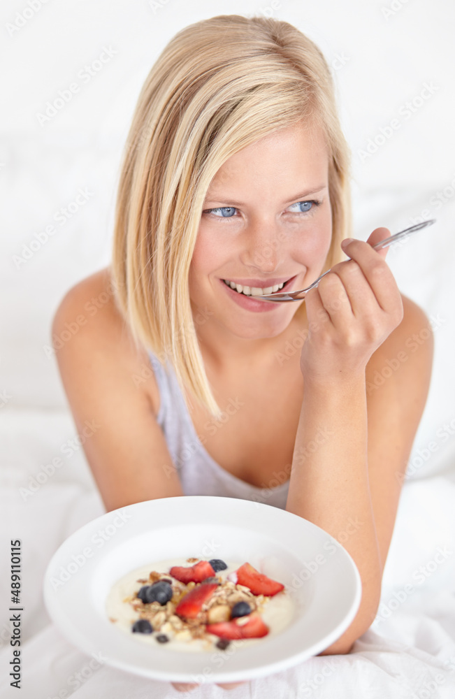 Breakfast in bed. An attractive young woman eating her breakfast in bed.