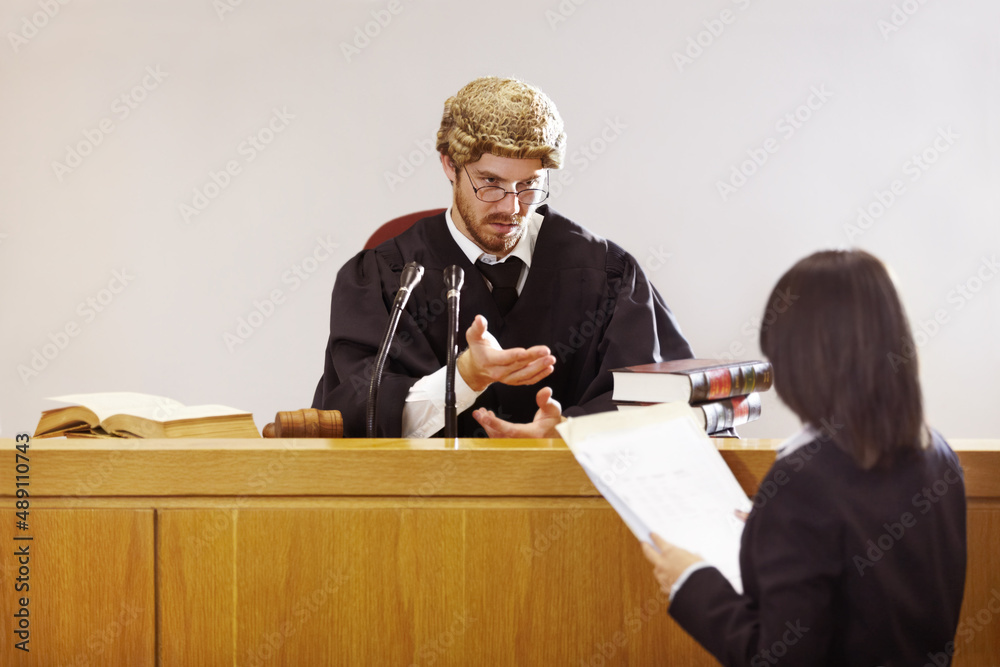 Present your case.... Serious young judge sitting in the courtroom with a stern facial expression.