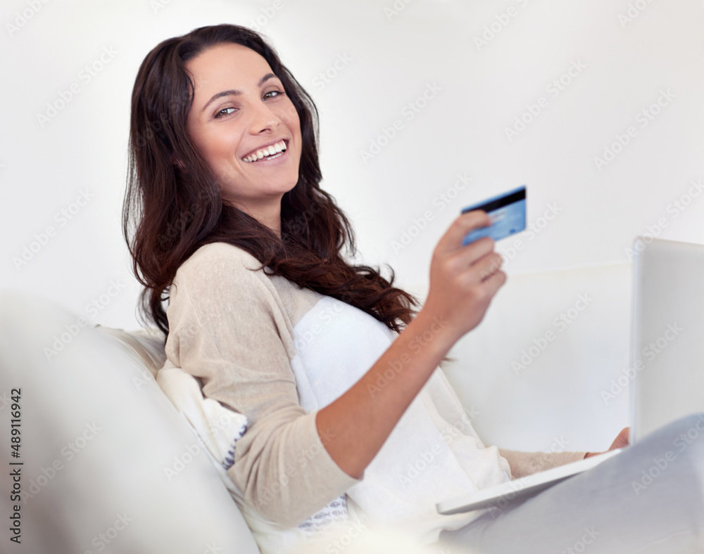 Shopping is just a click away. Portrait of an attractive woman holding a credit card while using a l