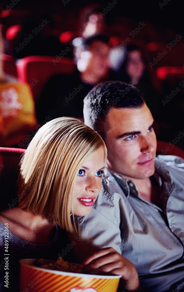 Here comes the scary part.... A cute young couple watching a scary movie in a cinema together.