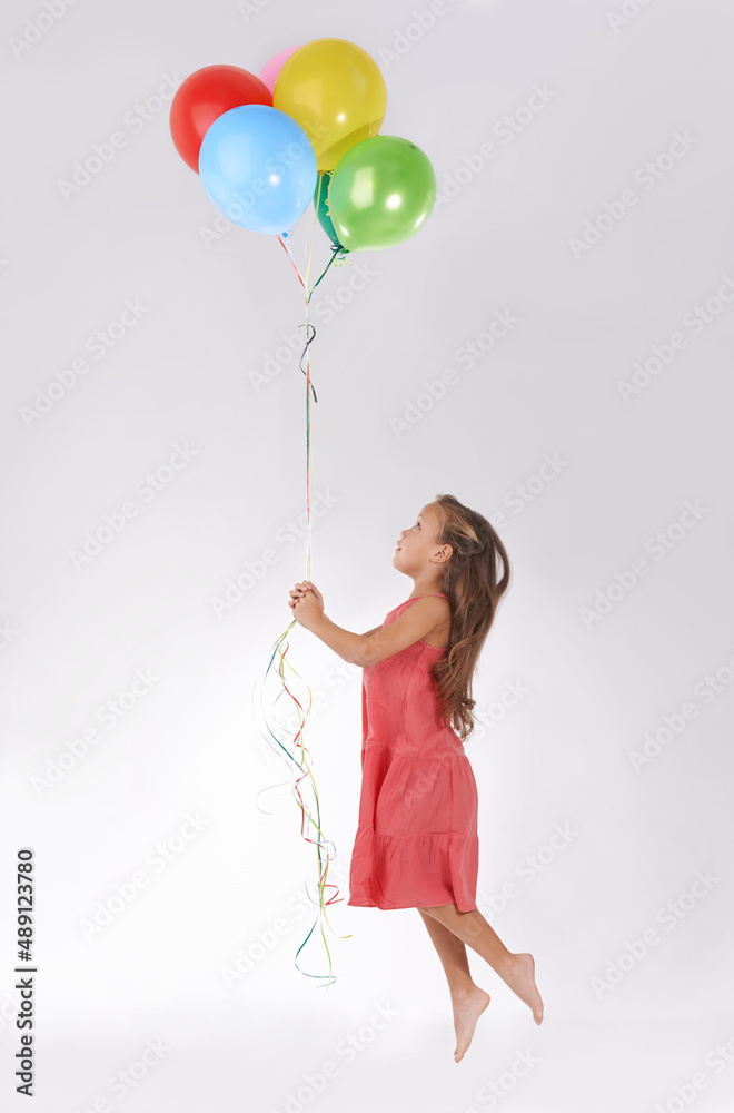 Floating away. A young girl being lifted in the air by a bunch of colourful balloons.