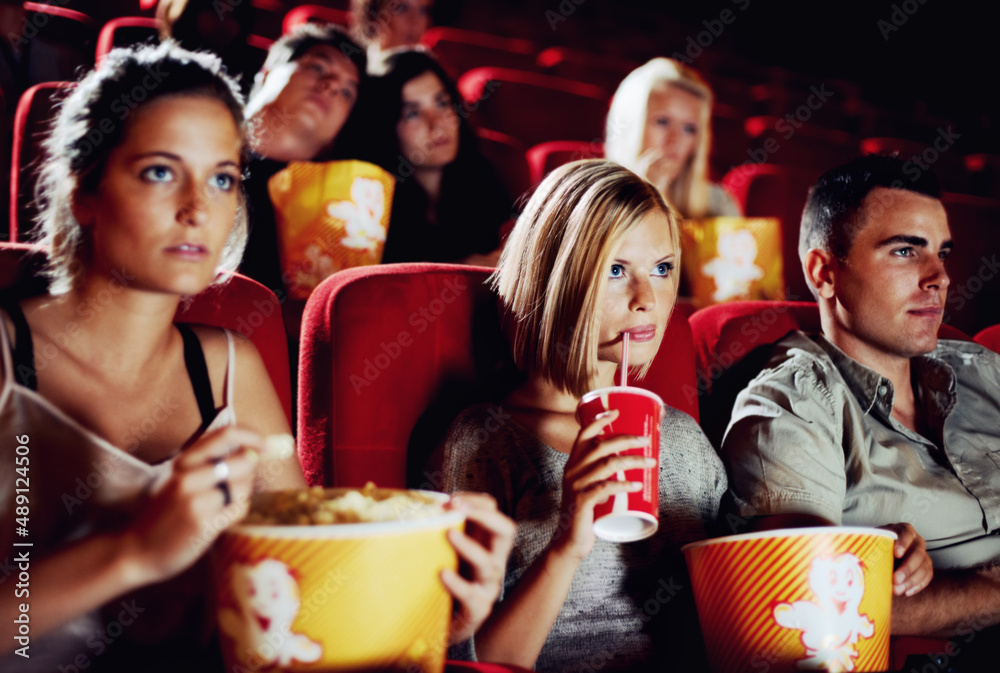 Sweet suspense. Friends sitting with refreshments and popcorn enjoying a movie together.